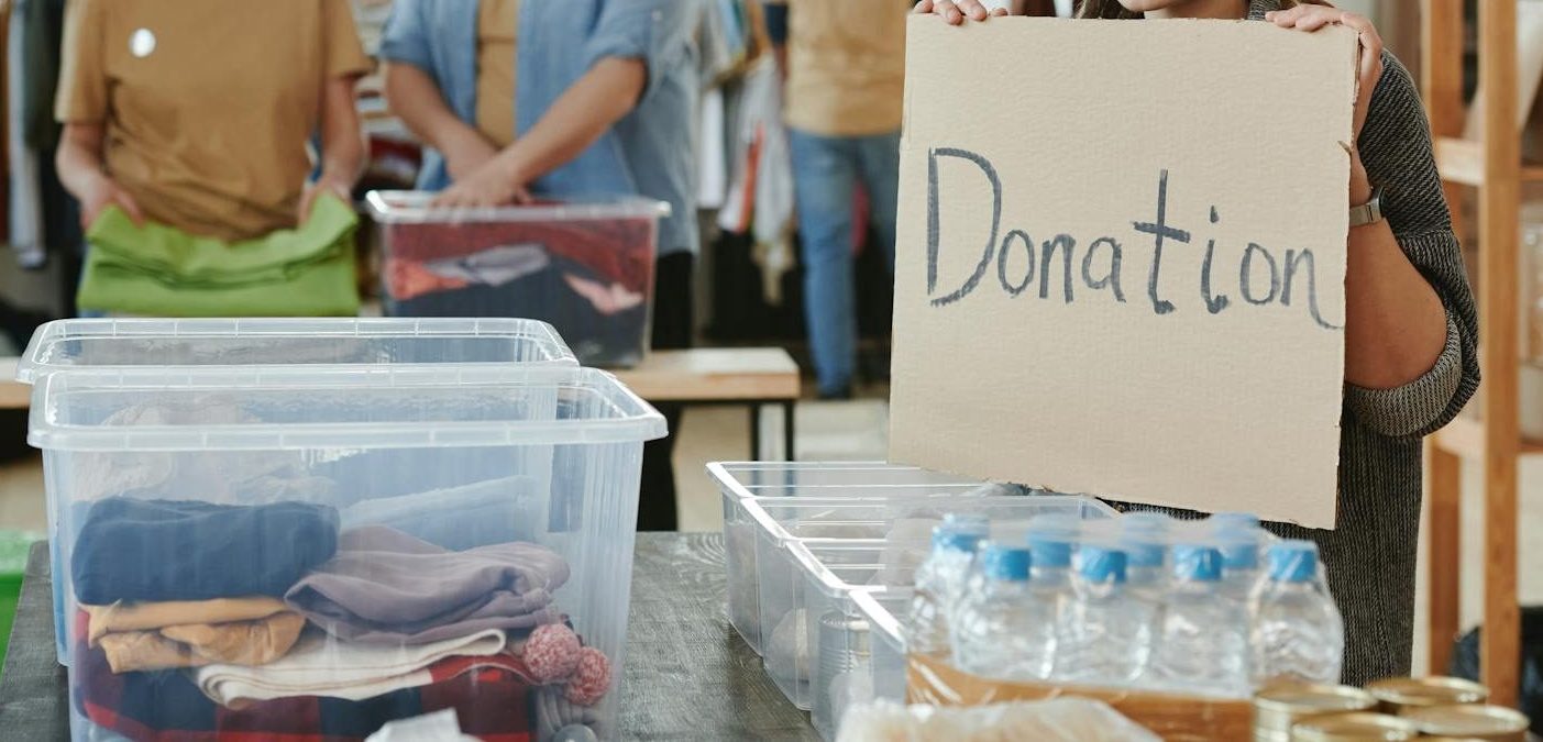 Group of volunteers organizing clothing and water donations indoors.